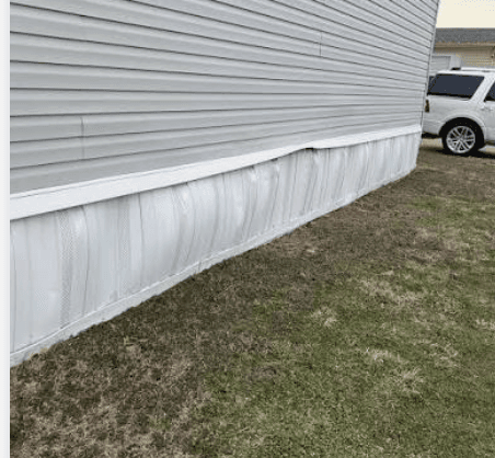 Damaged and buckled mobile home skirting before replacement