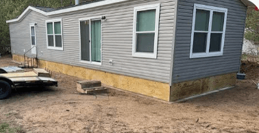 Mobile home with unfinished wooden skirting before completion