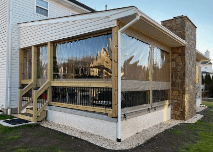 Enclosed porch addition with clear vinyl panels and stone chimney