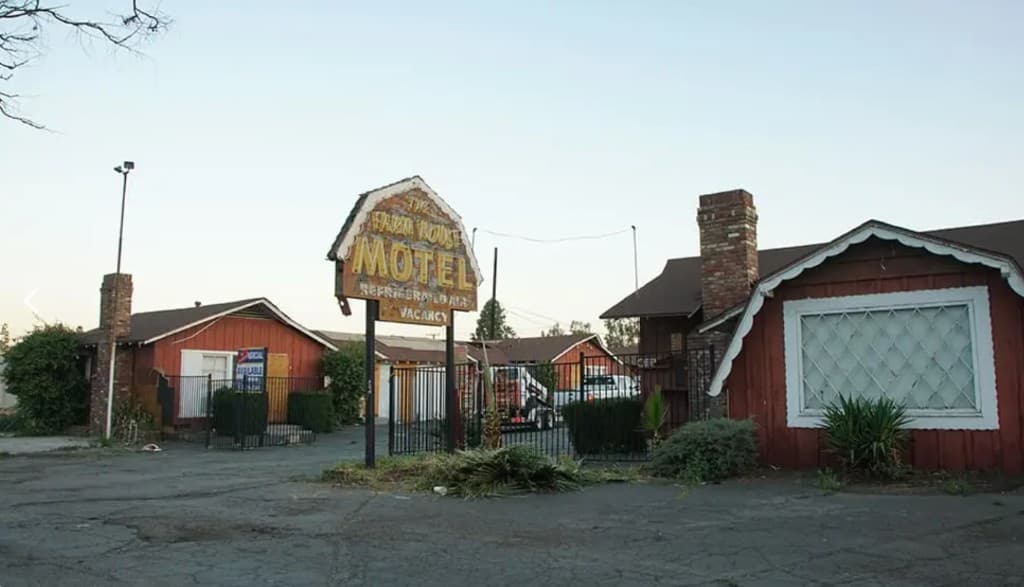 The Farm House Motel before restoration — weathered sign and red wood buildings in Riverside